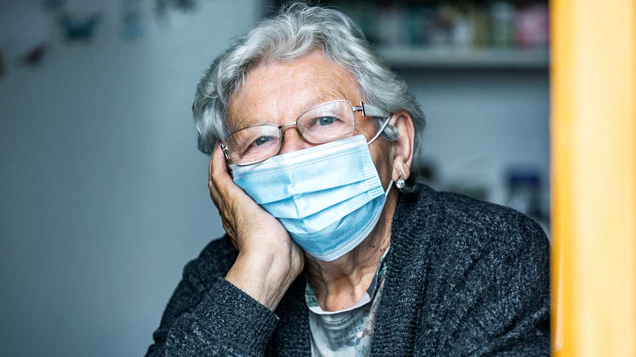 Nachdenkliche Seniorin mit Gesichtsmaske
