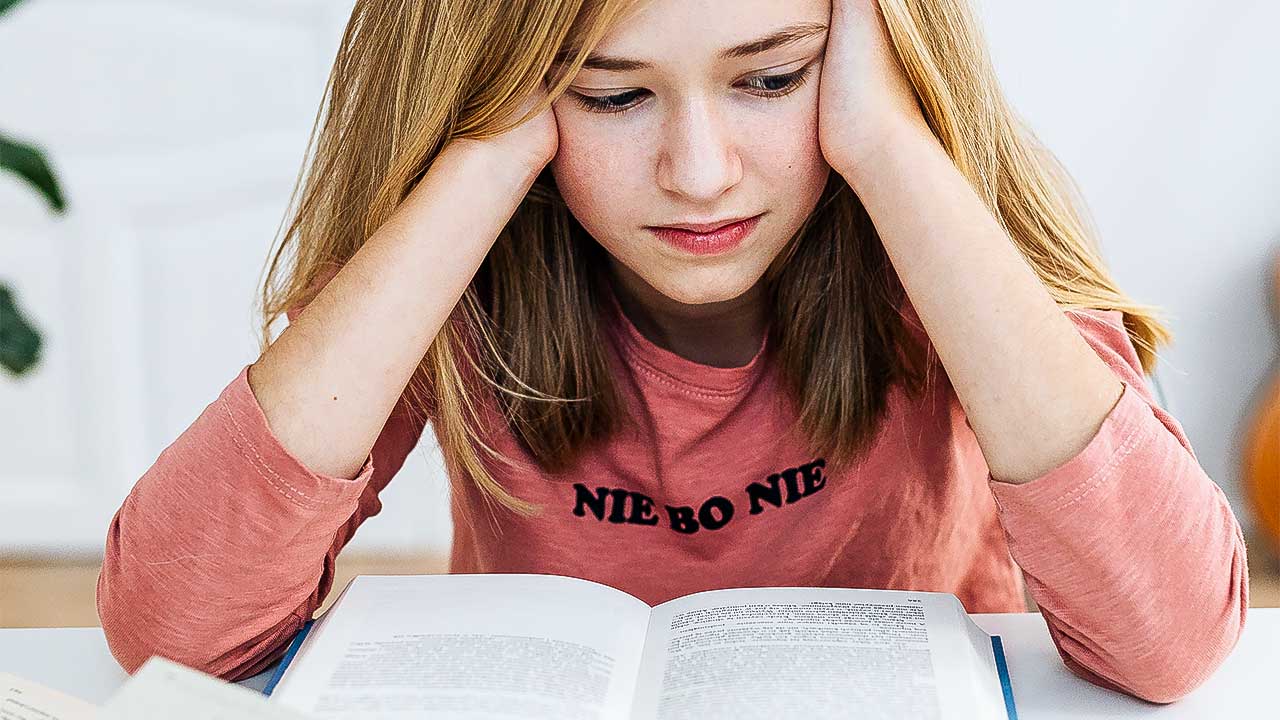 Mädchen sitzt nachdenklich über Büchern